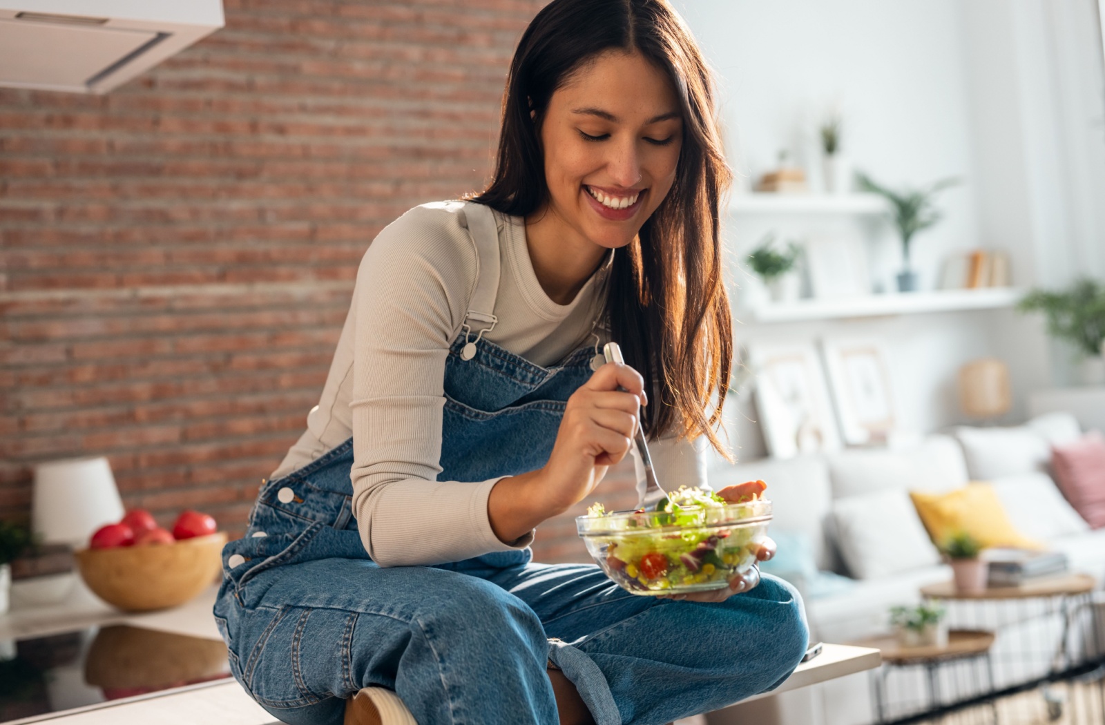 A young woman eating a balanced meal to further maintain her oral health at the recommendation of her biological dentist.
