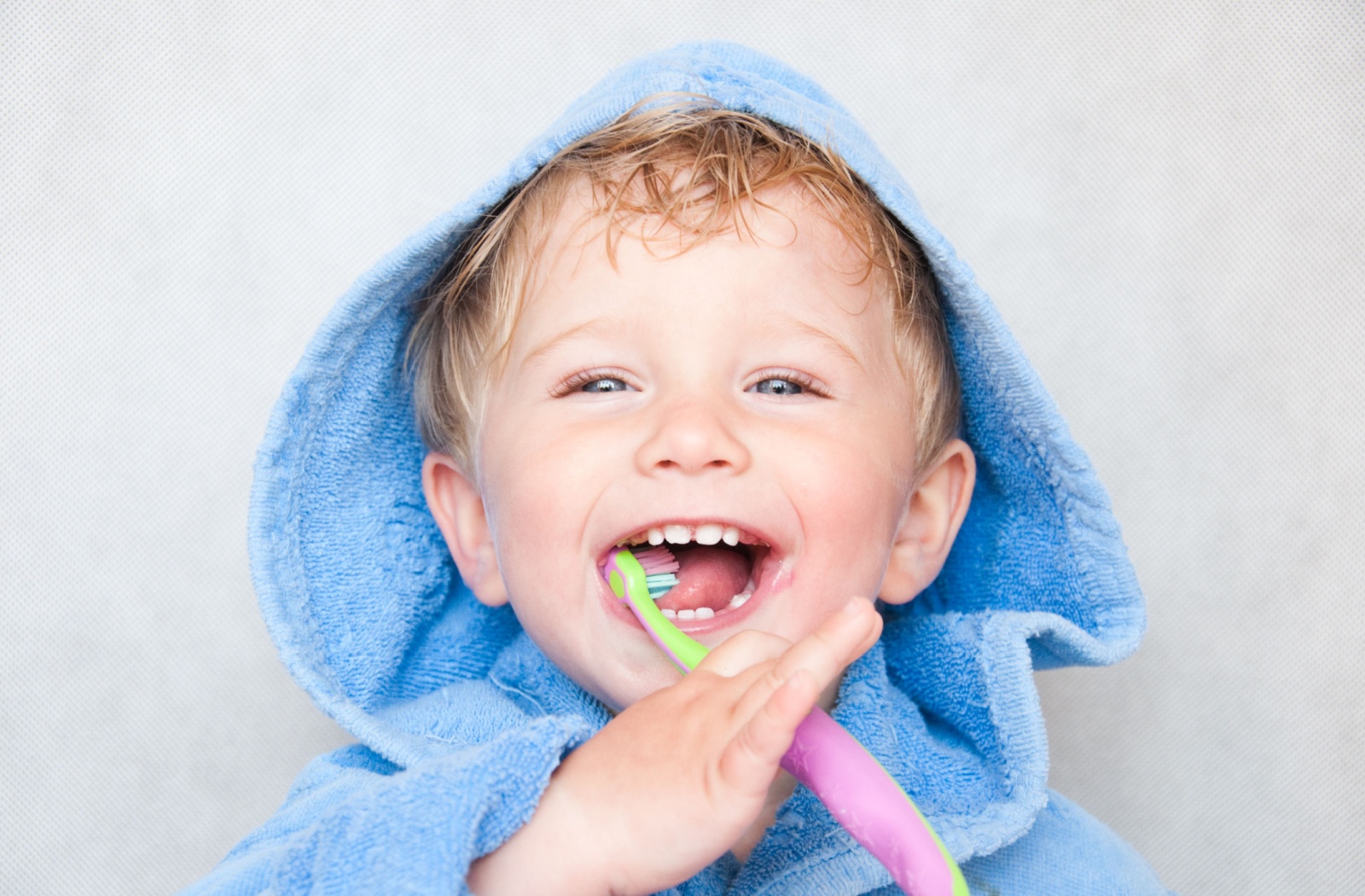 A young child happily brushing their teeth.