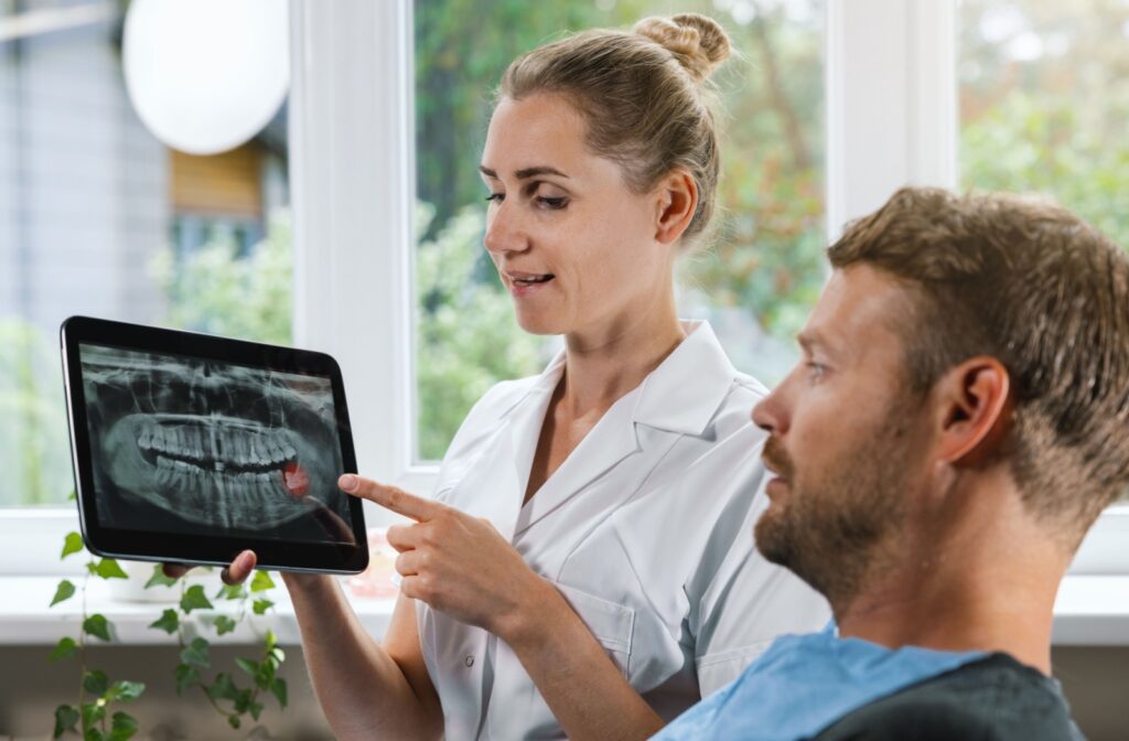 A dentist reviews their patient's digital X-rays with them on a tablet.