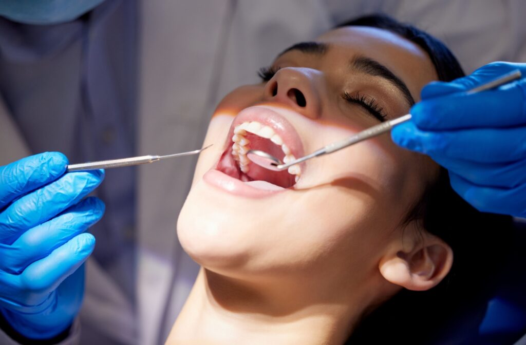 Patient laying back with their mouth open getting a dental inspection.