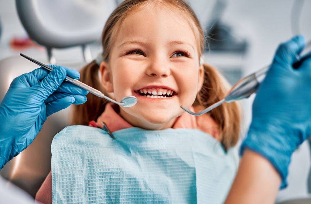 A young dental patient, smiling while having their teeth examined by a dentist.