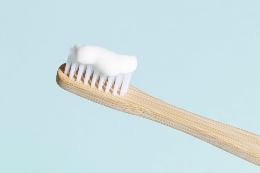 Eco-friendly bamboo toothbrush with white toothpaste on natural bristles for holistic dental care routine.